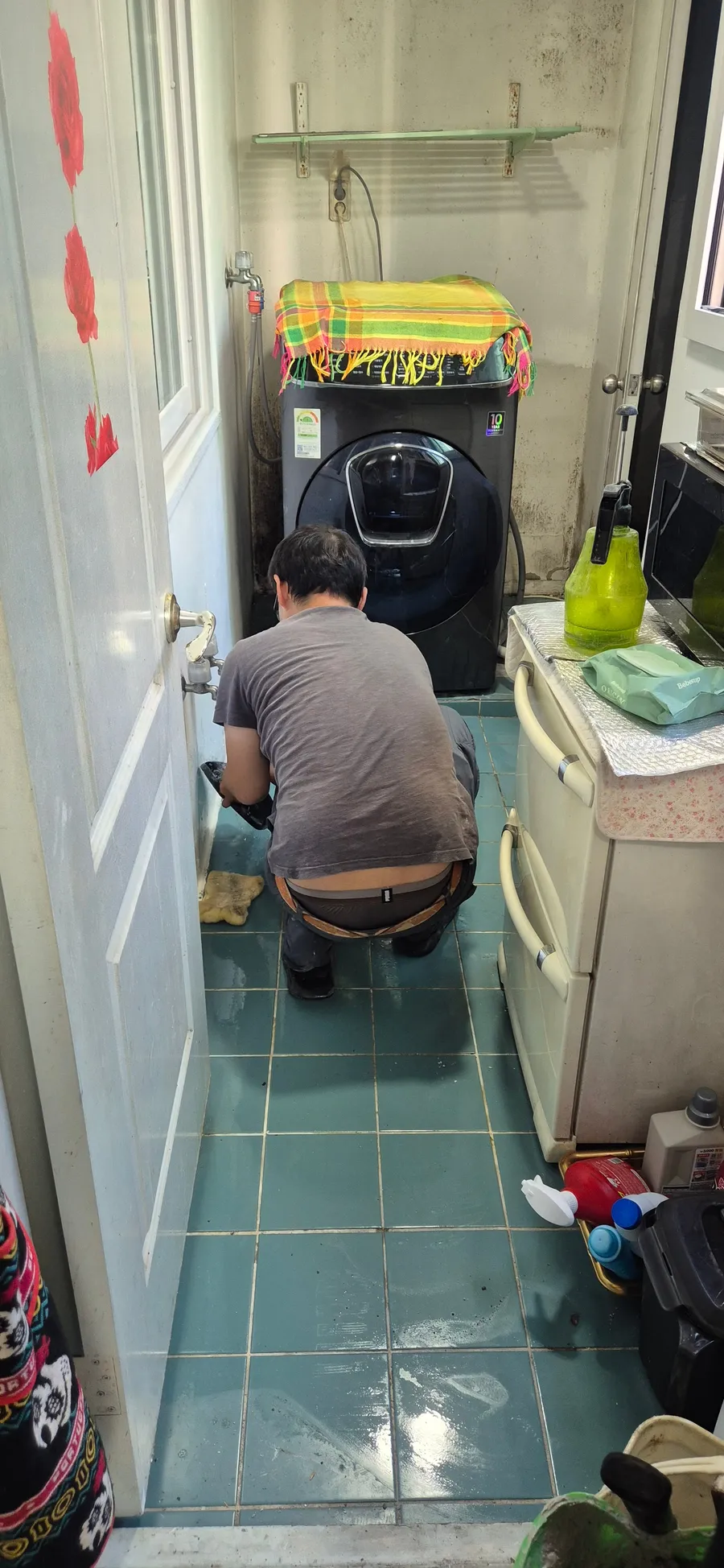 세탁실 벽 쪽 배관을 살피는 모습